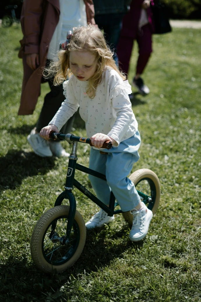 a little girl riding a small bike in the grass